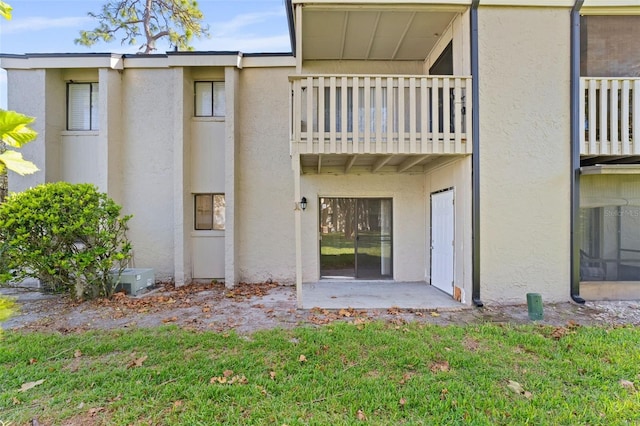 back of property with a balcony and a lawn