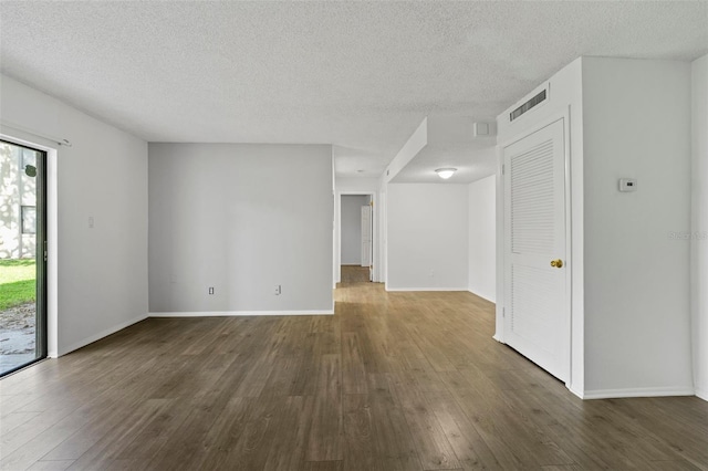 empty room featuring a textured ceiling and dark hardwood / wood-style floors