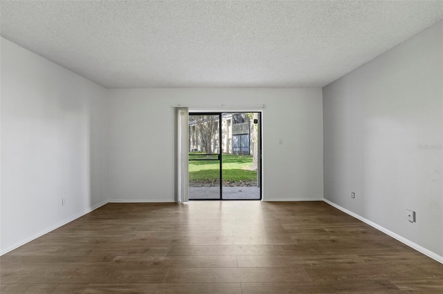 empty room with dark wood-type flooring and a textured ceiling