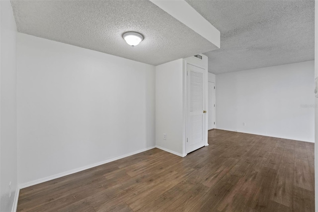 empty room with a textured ceiling and dark hardwood / wood-style flooring