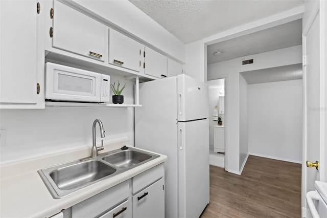 kitchen with sink, white cabinetry, white appliances, a textured ceiling, and dark hardwood / wood-style floors