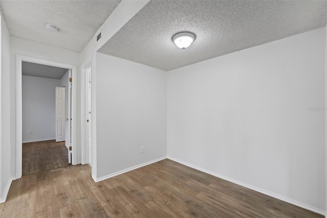 unfurnished room featuring hardwood / wood-style flooring and a textured ceiling