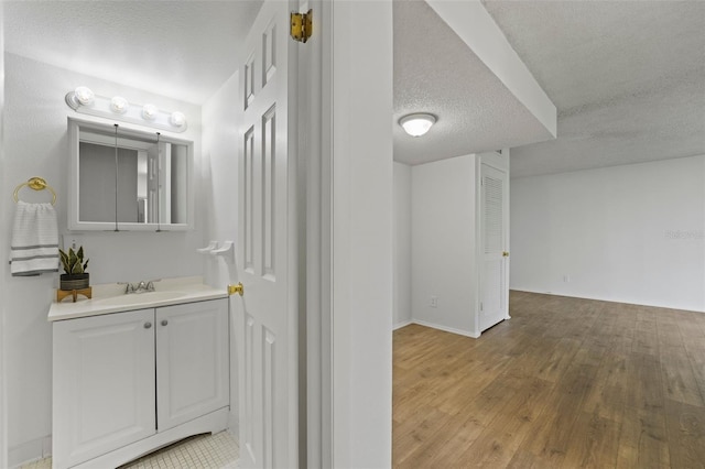 bathroom with hardwood / wood-style floors, a textured ceiling, and vanity