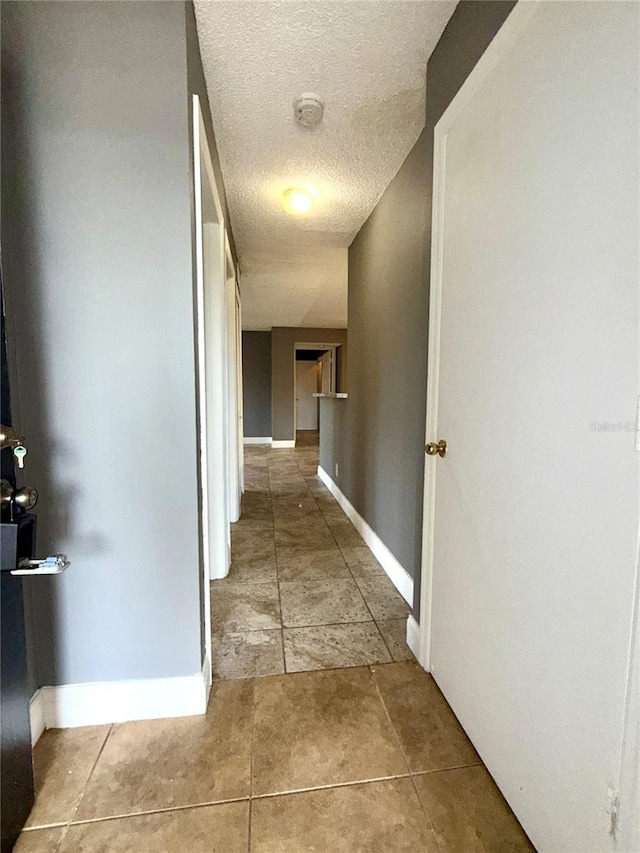 corridor featuring light tile patterned floors and a textured ceiling