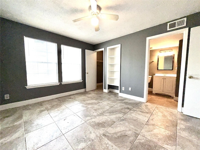 unfurnished bedroom featuring ceiling fan, a textured ceiling, connected bathroom, and a closet