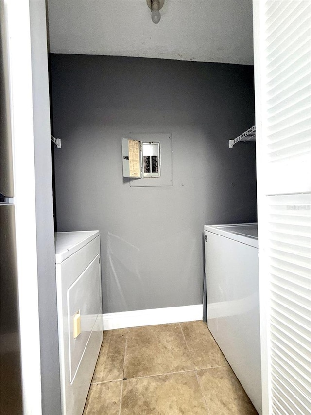 laundry area with light tile patterned floors, electric panel, and washer and clothes dryer