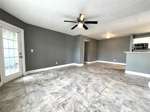 unfurnished living room featuring ceiling fan and a textured ceiling