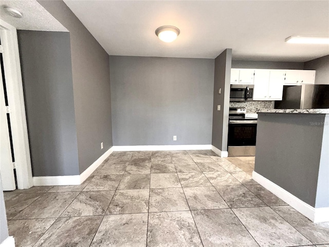 kitchen with white cabinets, light stone countertops, stainless steel appliances, and tasteful backsplash