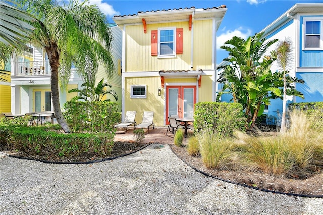 view of front of property with french doors, a patio, and a balcony