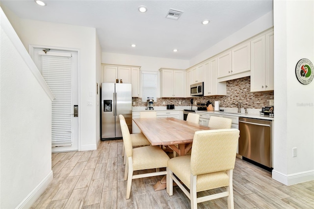 kitchen featuring sink, light hardwood / wood-style floors, decorative backsplash, a breakfast bar, and appliances with stainless steel finishes