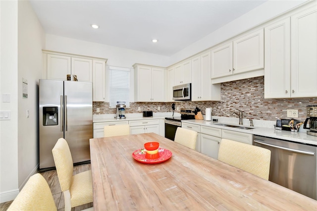 kitchen with white cabinets, backsplash, sink, and stainless steel appliances