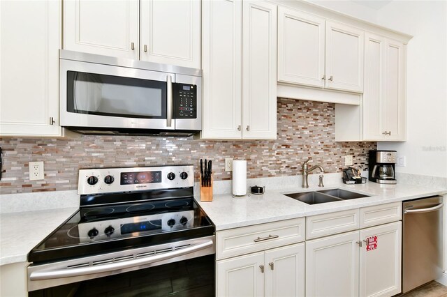 kitchen featuring tasteful backsplash, sink, white cabinets, and stainless steel appliances