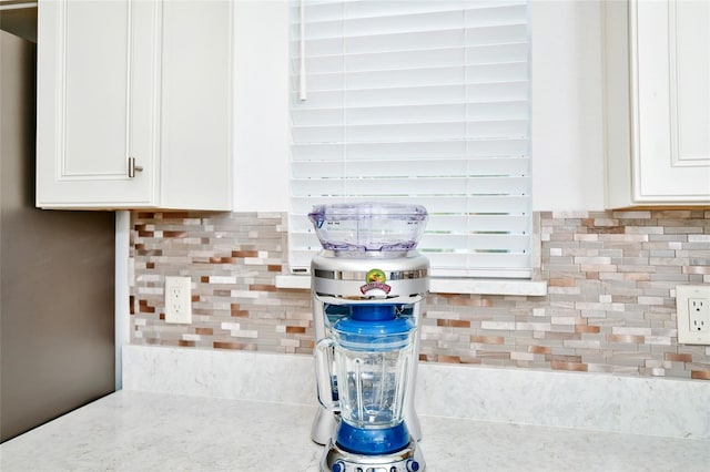 details with white cabinetry, light stone countertops, and tasteful backsplash