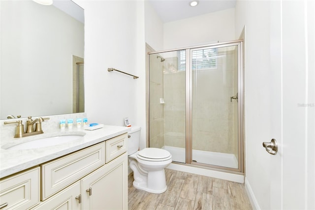 bathroom featuring wood-type flooring, vanity, toilet, and a shower with shower door