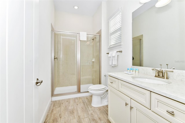 bathroom featuring vanity, hardwood / wood-style flooring, toilet, and a shower with door