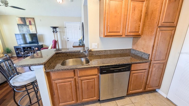 kitchen with dishwasher, a breakfast bar, sink, dark stone countertops, and kitchen peninsula