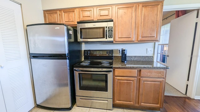 kitchen featuring dark stone countertops, light hardwood / wood-style floors, and appliances with stainless steel finishes