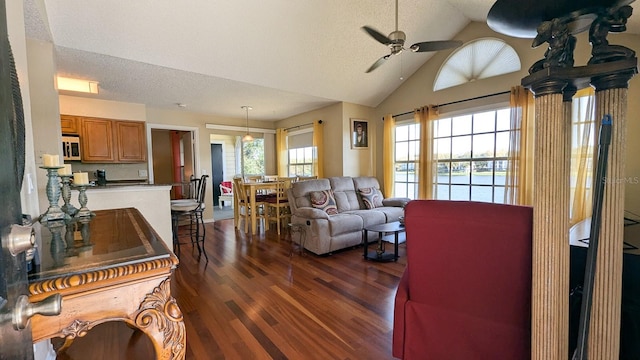 living room featuring dark hardwood / wood-style floors, ceiling fan, lofted ceiling, and a textured ceiling