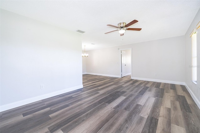 empty room featuring ceiling fan with notable chandelier and dark wood-type flooring