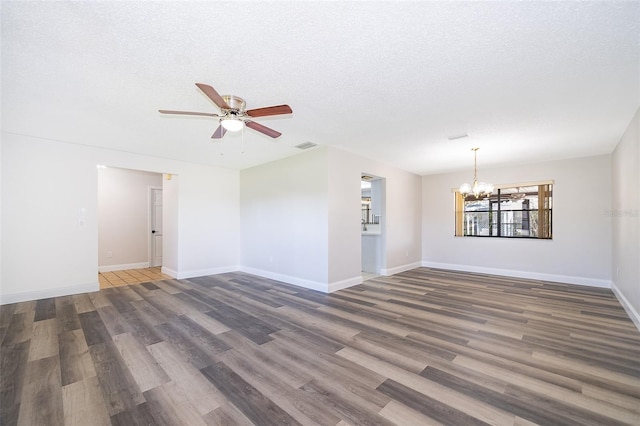 spare room with a textured ceiling, ceiling fan with notable chandelier, and dark hardwood / wood-style floors