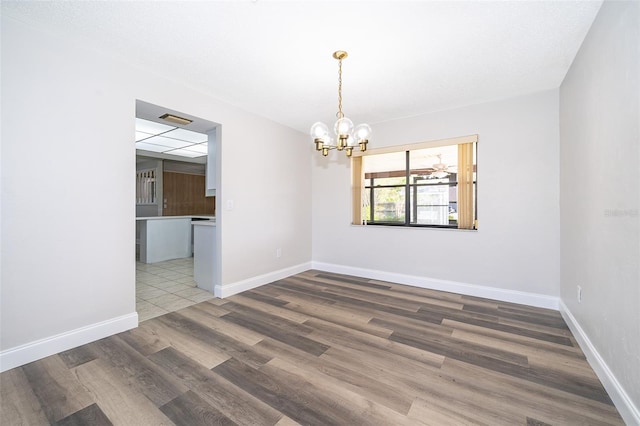 empty room with dark wood-type flooring and a notable chandelier