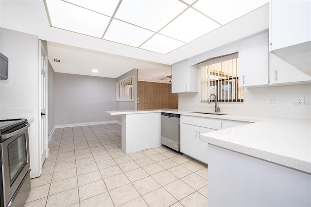 kitchen with kitchen peninsula, appliances with stainless steel finishes, sink, light tile patterned floors, and white cabinets