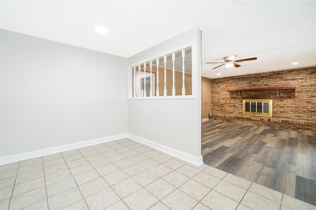 interior space featuring a fireplace, ceiling fan, light hardwood / wood-style flooring, and brick wall