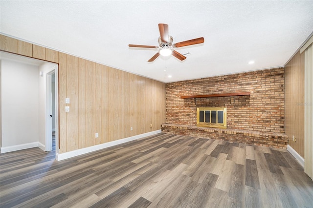 unfurnished living room with a textured ceiling, wooden walls, brick wall, and dark hardwood / wood-style floors