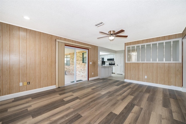 unfurnished living room featuring dark hardwood / wood-style flooring, a textured ceiling, and wooden walls