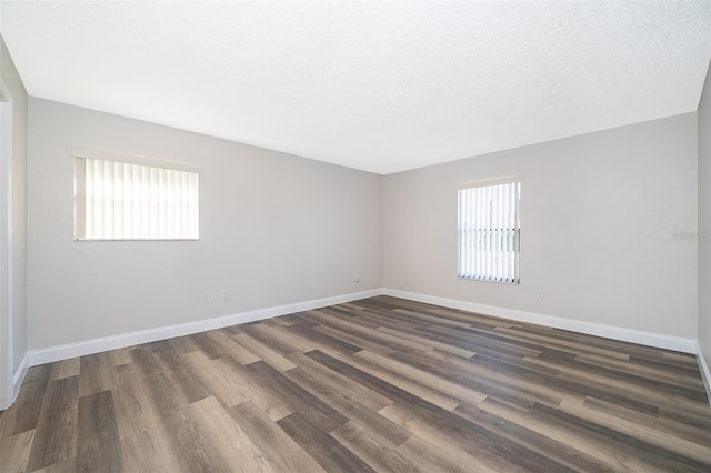 empty room featuring dark hardwood / wood-style flooring, plenty of natural light, and a textured ceiling