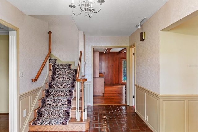 staircase with a notable chandelier and track lighting