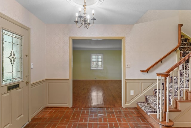 entryway featuring hardwood / wood-style flooring, crown molding, and a notable chandelier