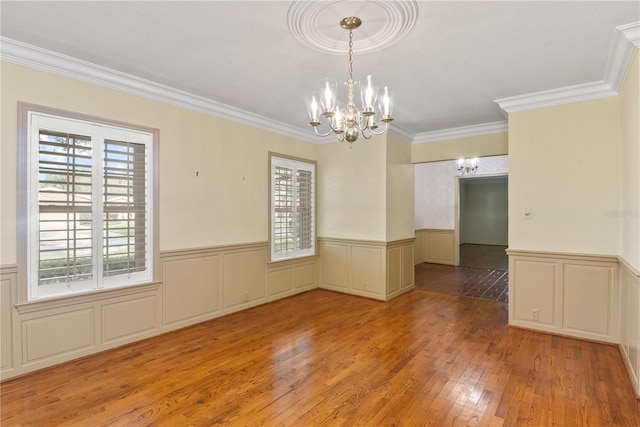 unfurnished room with ornamental molding, a notable chandelier, and light wood-type flooring