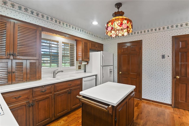 kitchen with dishwasher, sink, white refrigerator with ice dispenser, pendant lighting, and light wood-type flooring