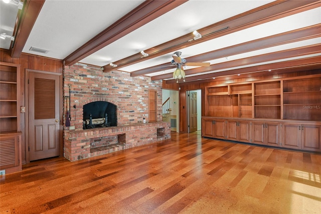 unfurnished living room featuring beam ceiling, wood walls, ceiling fan, and light wood-type flooring