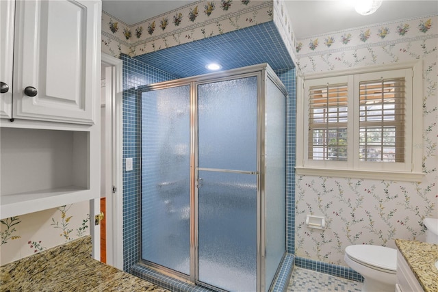 bathroom with vanity, toilet, and a shower with door