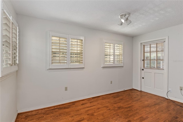 empty room with wood-type flooring and a textured ceiling