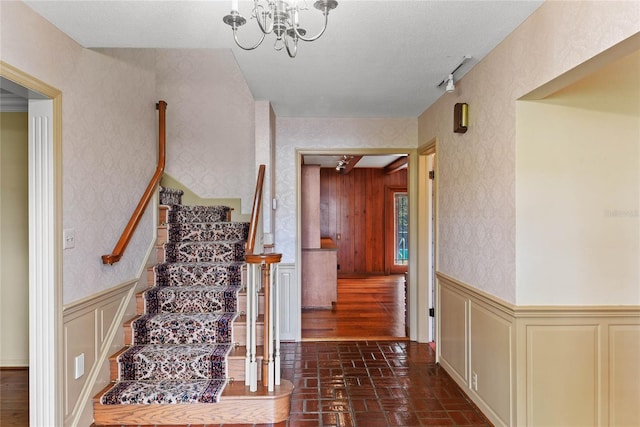 staircase featuring a textured ceiling and an inviting chandelier