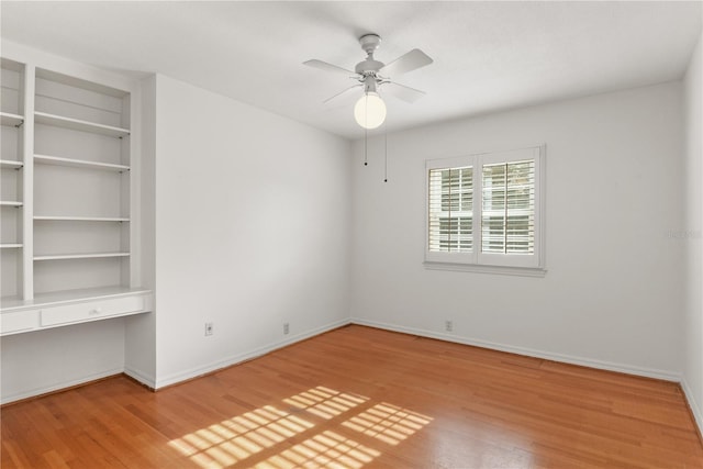 spare room with ceiling fan, hardwood / wood-style floors, and built in desk