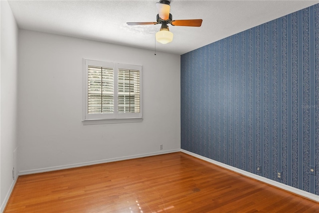 empty room with ceiling fan, hardwood / wood-style floors, and a textured ceiling