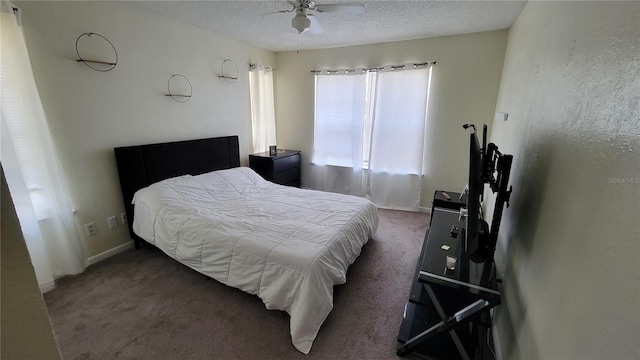 bedroom featuring a textured ceiling, dark carpet, and ceiling fan