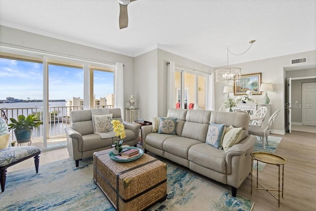 living room with ceiling fan with notable chandelier, light wood-type flooring, and a water view