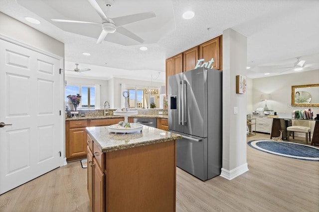 134 Starboard Ln Unit 705, Merritt Island, FL 32953 - kitchen with stainless steel appliances, ceiling fan, brown cabinetry, a center island, and light wood-style floors