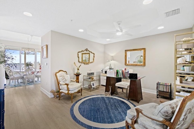 office space featuring ceiling fan with notable chandelier and light wood-type flooring