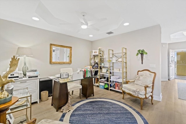 office featuring a raised ceiling, ceiling fan, and light hardwood / wood-style floors