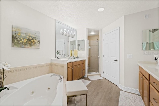 bathroom featuring vanity, wood-type flooring, a textured ceiling, and separate shower and tub