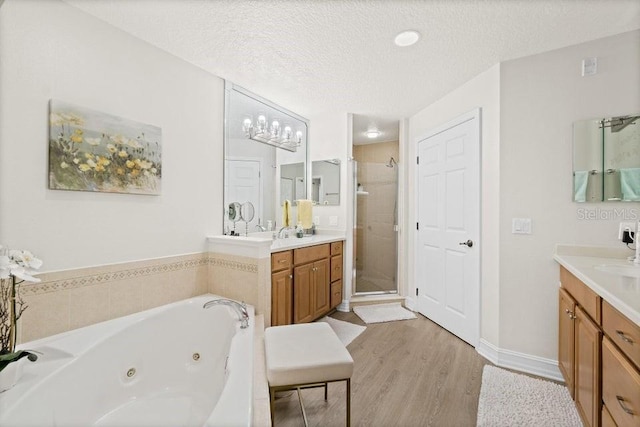 134 Starboard Ln Unit 705, Merritt Island, FL 32953 - full bathroom with a stall shower, wood finished floors, a tub with jets, two vanities, and a textured ceiling