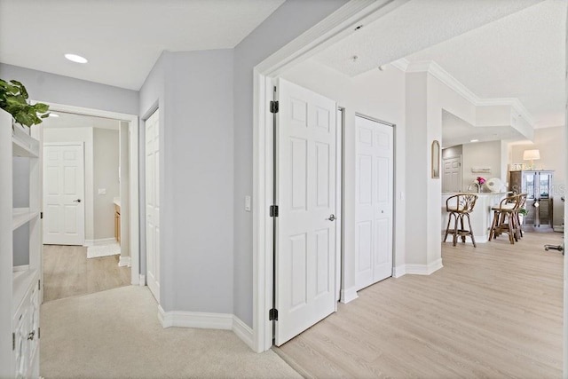 corridor with light wood-type flooring and ornamental molding