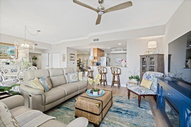 living room with crown molding, hardwood / wood-style floors, and ceiling fan with notable chandelier