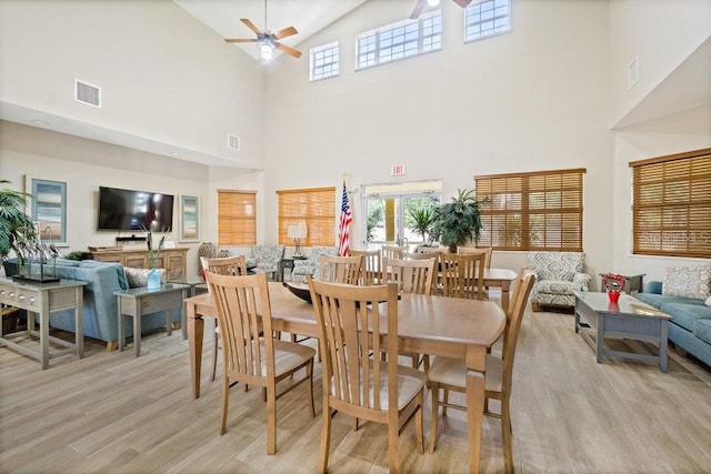 dining space featuring ceiling fan, light hardwood / wood-style flooring, and a high ceiling